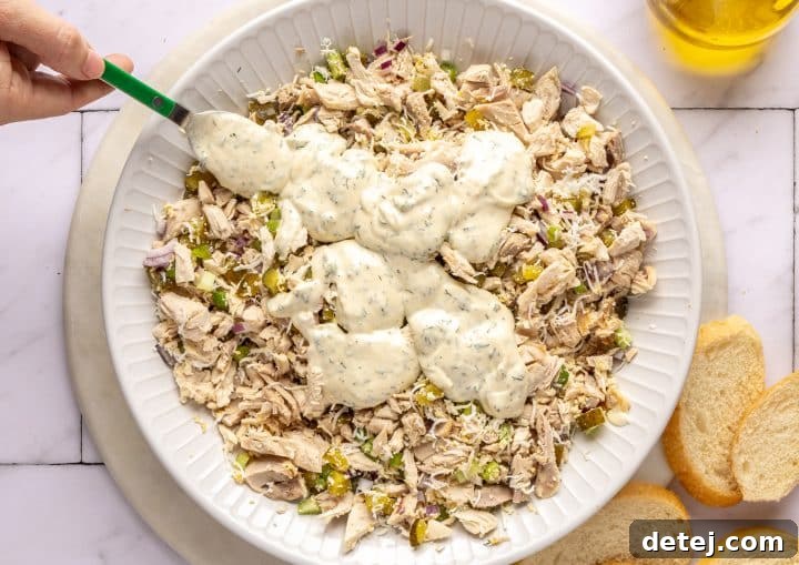 Dressing being poured over the chicken salad ingredients.
