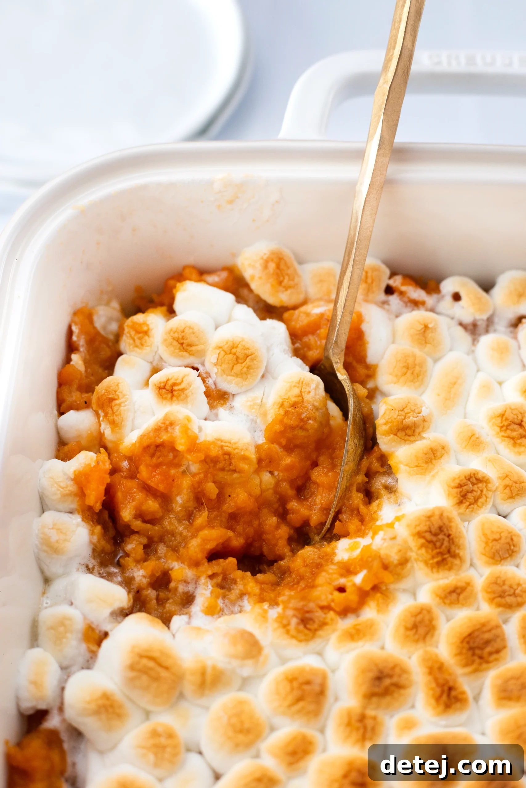 Sweet potato casserole filling in a baking dish, topped with a generous layer of mini marshmallows.