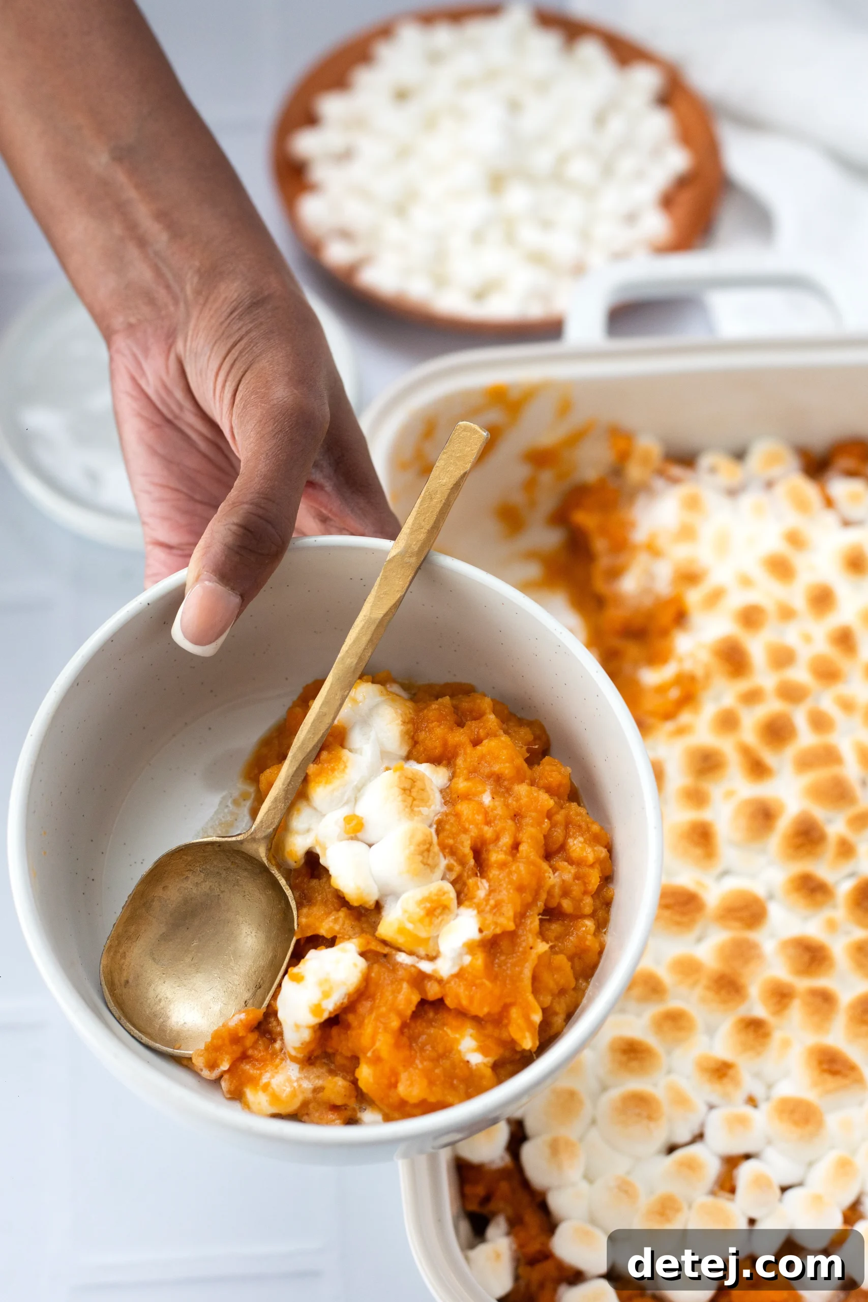 A slice of sweet potato casserole on a plate, showing the layers of sweet potato and marshmallow topping.
