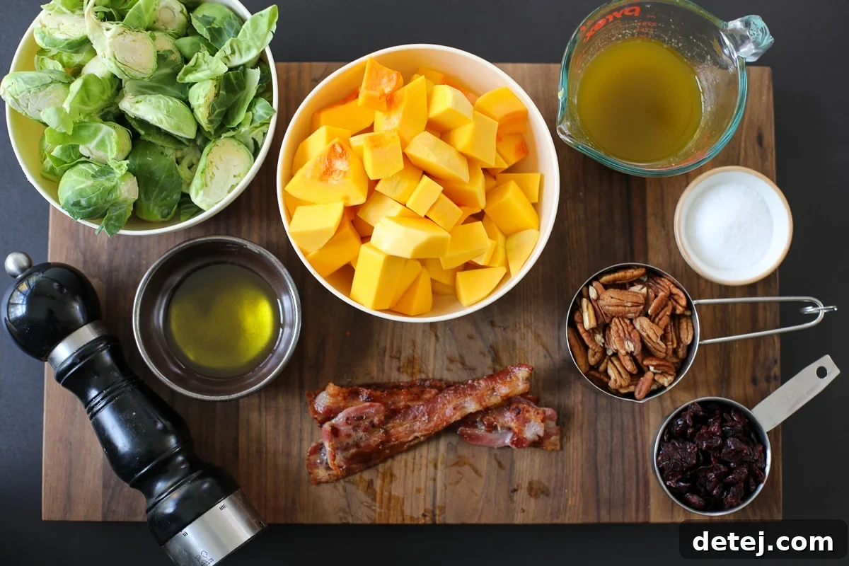 A close-up shot of all the fresh ingredients laid out before cooking, including butternut squash, Brussels sprouts, pecans, bacon, and cranberries.