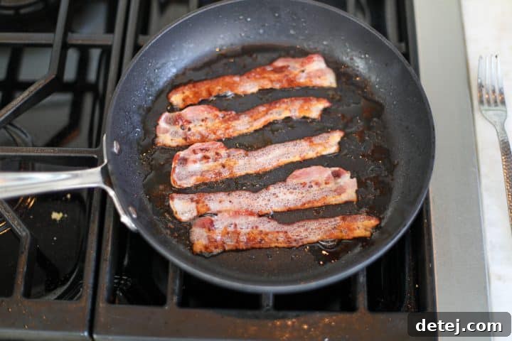 Crispy, golden-brown bacon slices resting in the pan after cooking, before being chopped.