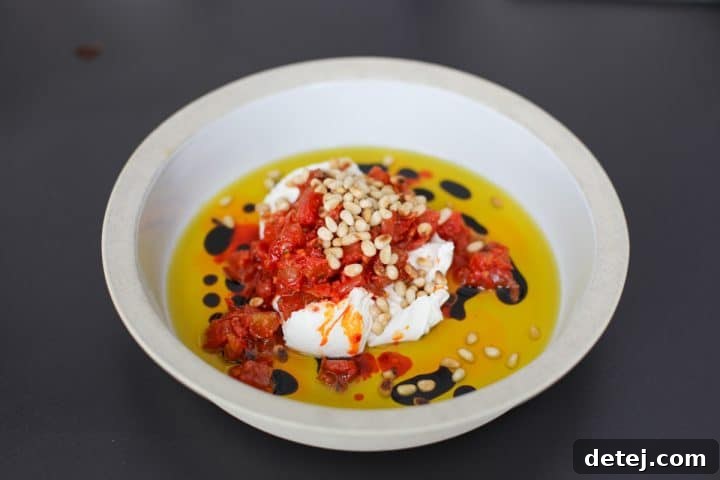 Luscious Burrata Bruschetta Dip 8 A serving bowl with the assembled dip including burrata, bruschetta, chili oil, and a scattering of toasted pine nuts for crunch.