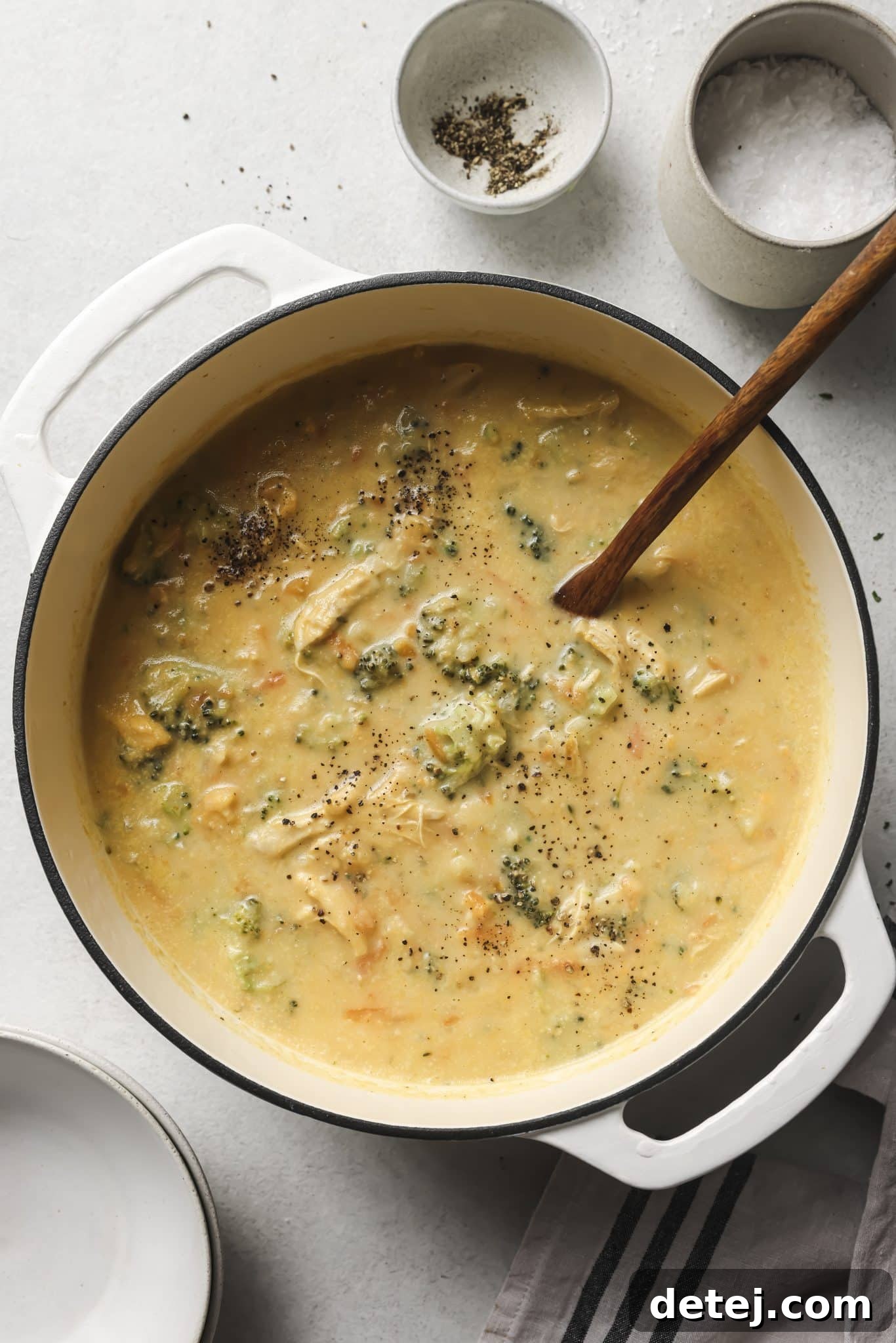 A large pot of creamy healthy chicken broccoli soup sits on a stovetop, ready to be served, highlighting its comforting nature.