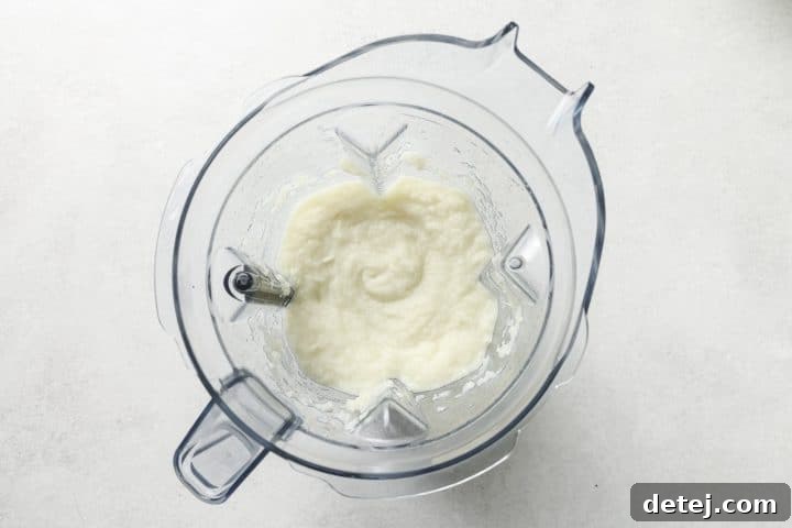 Smooth, creamy cauliflower puree in a food processor bowl, ready to be incorporated into the soup.