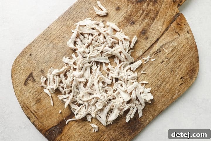 Finely shredded cooked chicken in a bowl, prepared for addition to the soup.