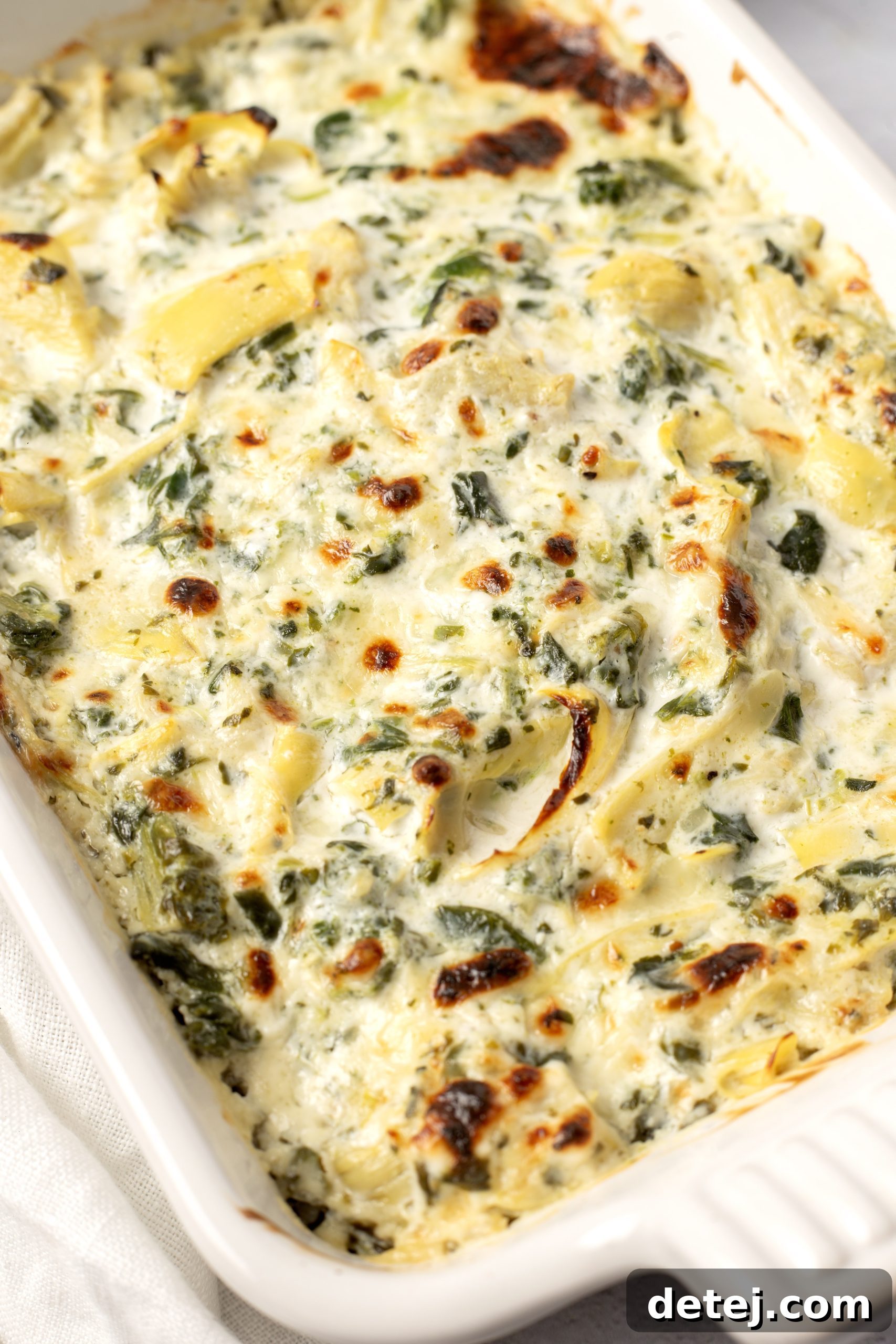 Close-up shot of creamy spinach artichoke dip with dippers.