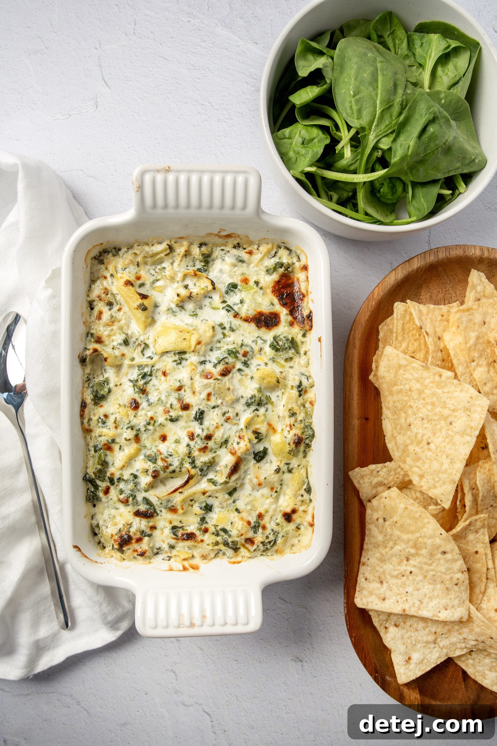 Various dippers arranged around a hot spinach artichoke dip.