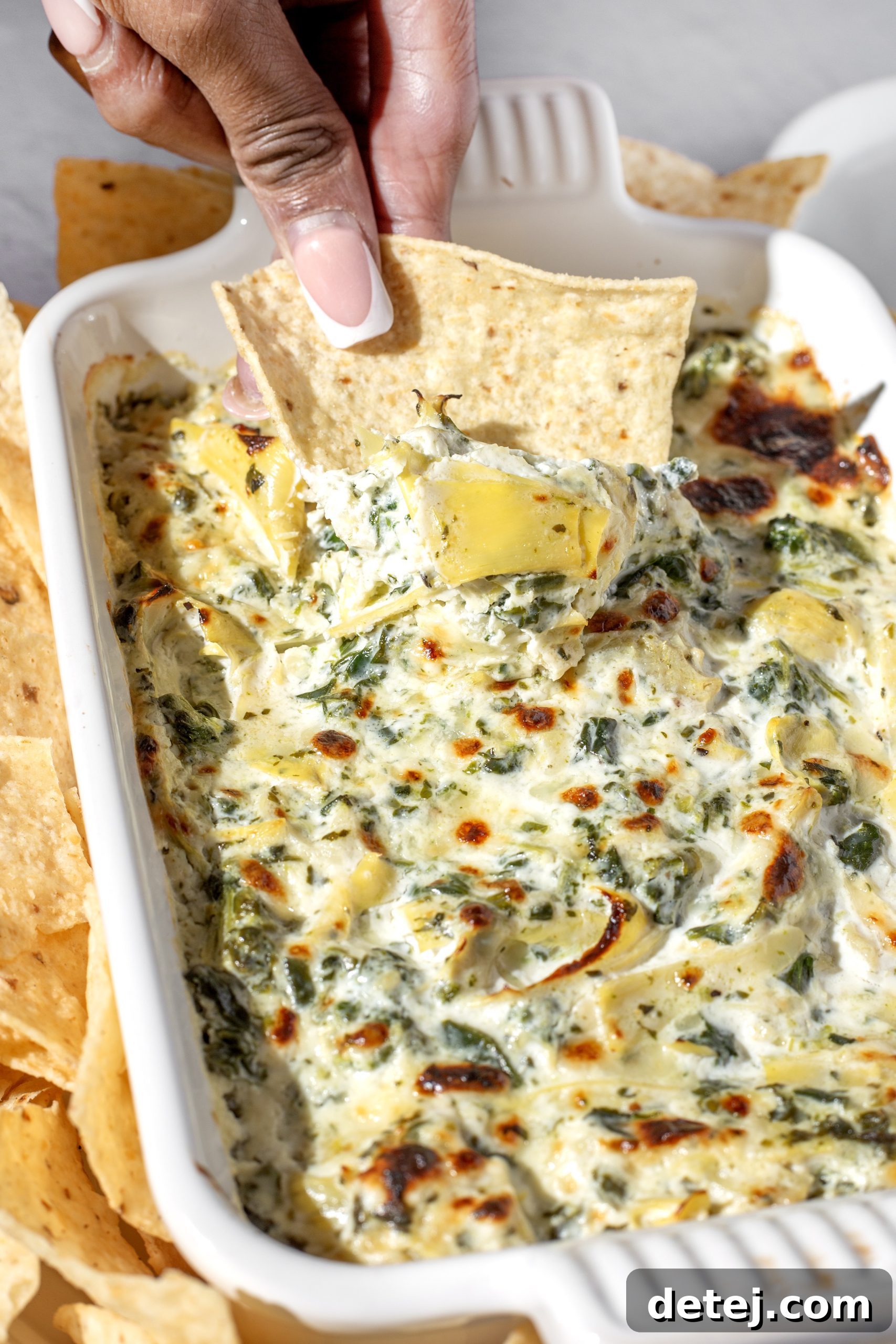 A serving of spinach artichoke dip, freshly broiled and bubbly.