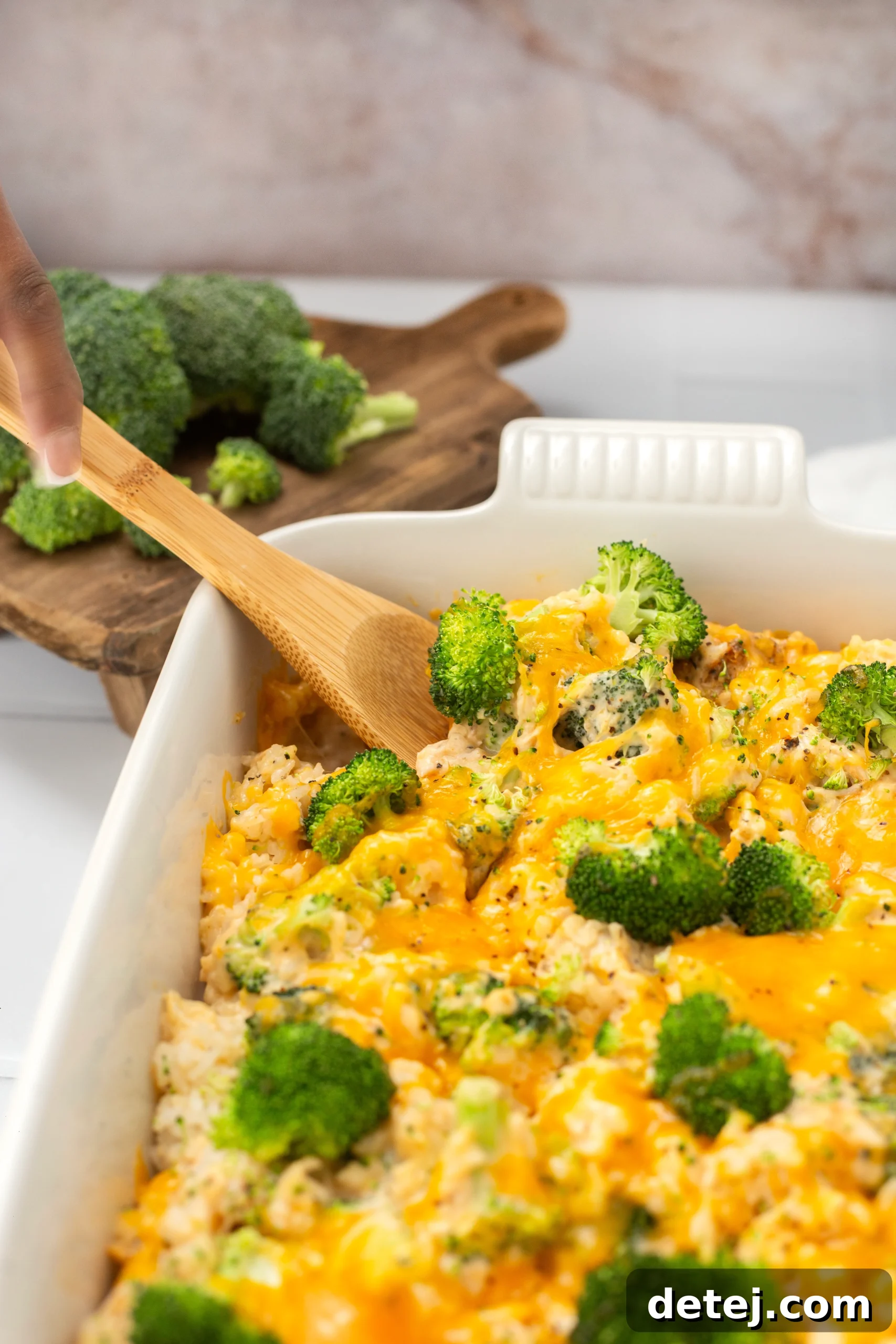 A golden-brown cheesy chicken broccoli rice casserole, hot and bubbly, being taken out of the oven.