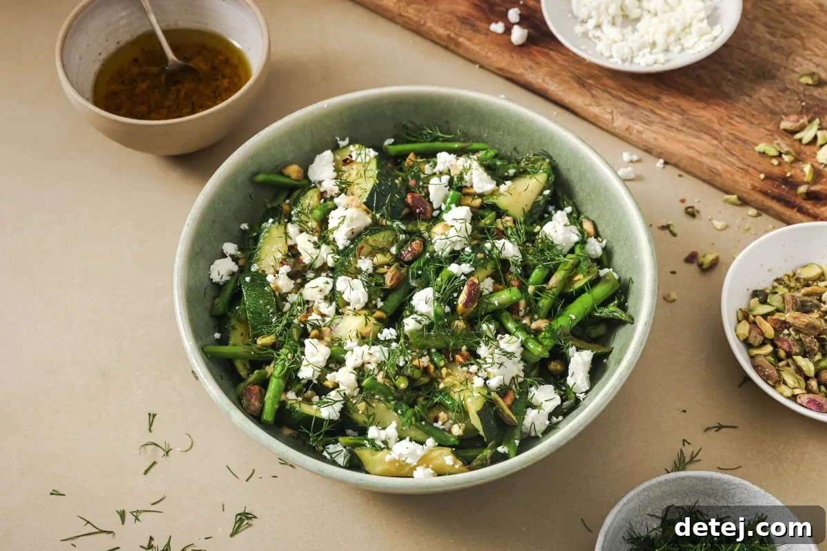 Overhead shot of the Sautéed Spring Vegetable Salad, highlighting the fresh herbs, crumbled feta, and crushed pistachios as toppings.