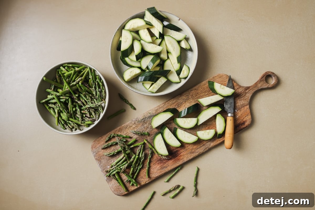 Prepped zucchini slices, asparagus pieces, and crushed pistachios, neatly arranged and ready for cooking and assembly.