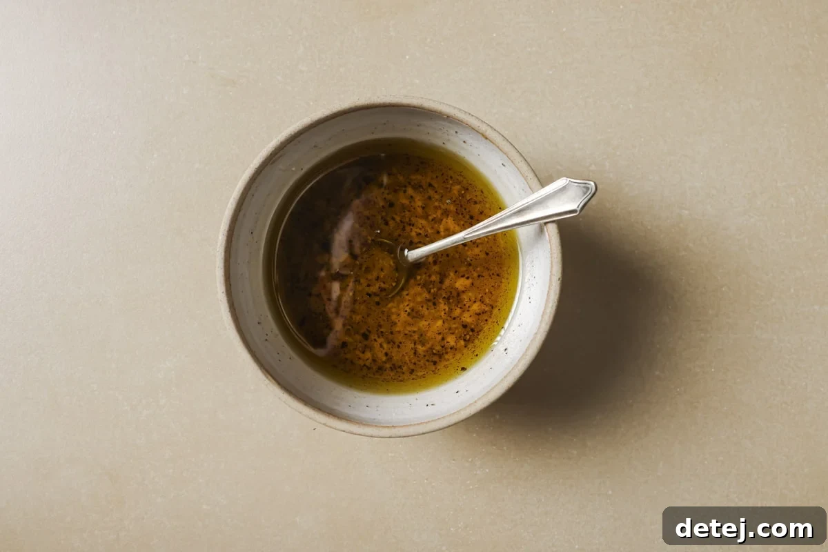 Ingredients for the lemon Dijon dressing, expertly mixed in a bowl, ready to enhance the warm vegetable salad.