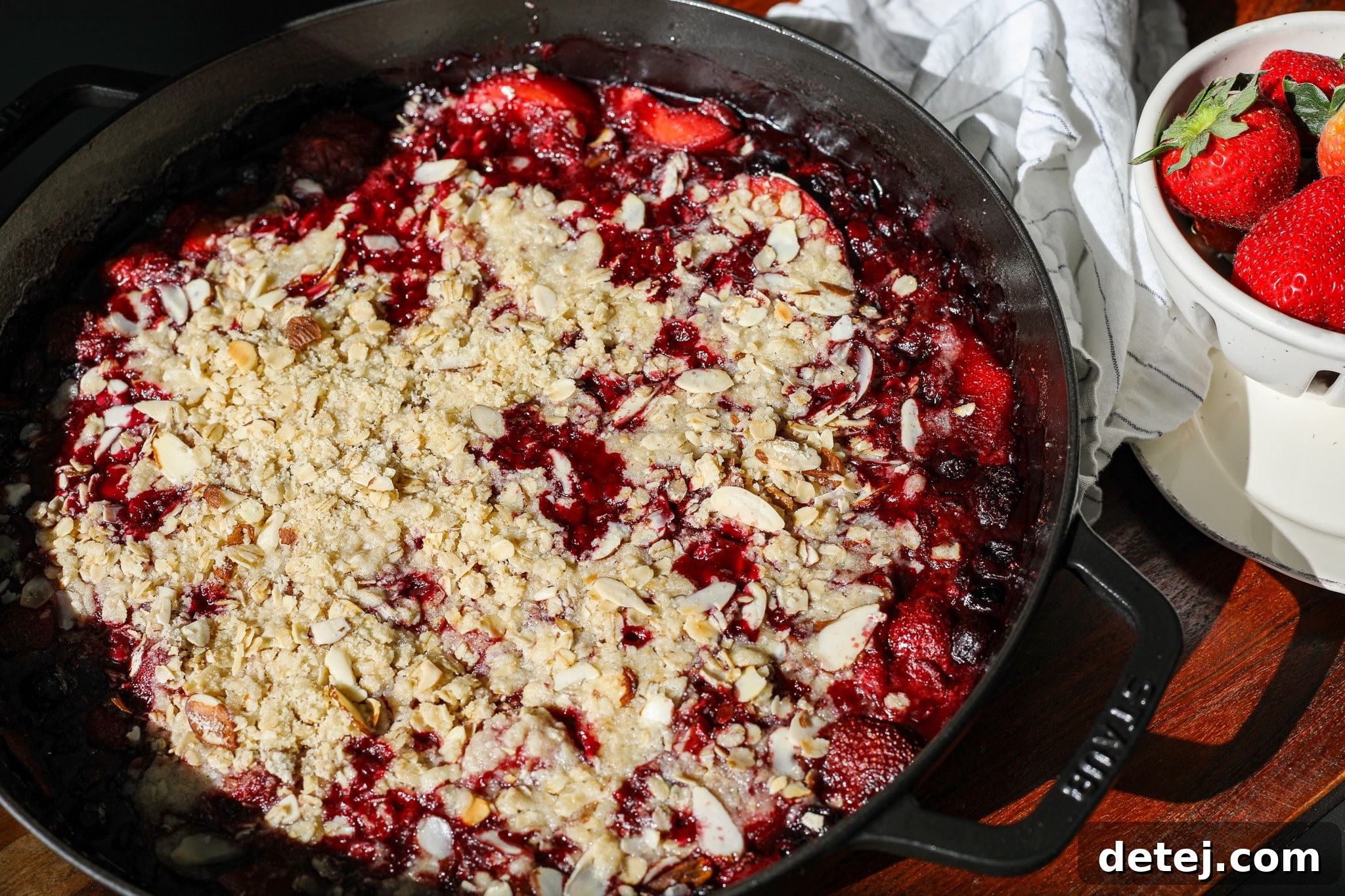 Close-up side view of the Peachberry Crisp, showcasing the golden crumb topping and juicy fruit filling bubbling underneath.