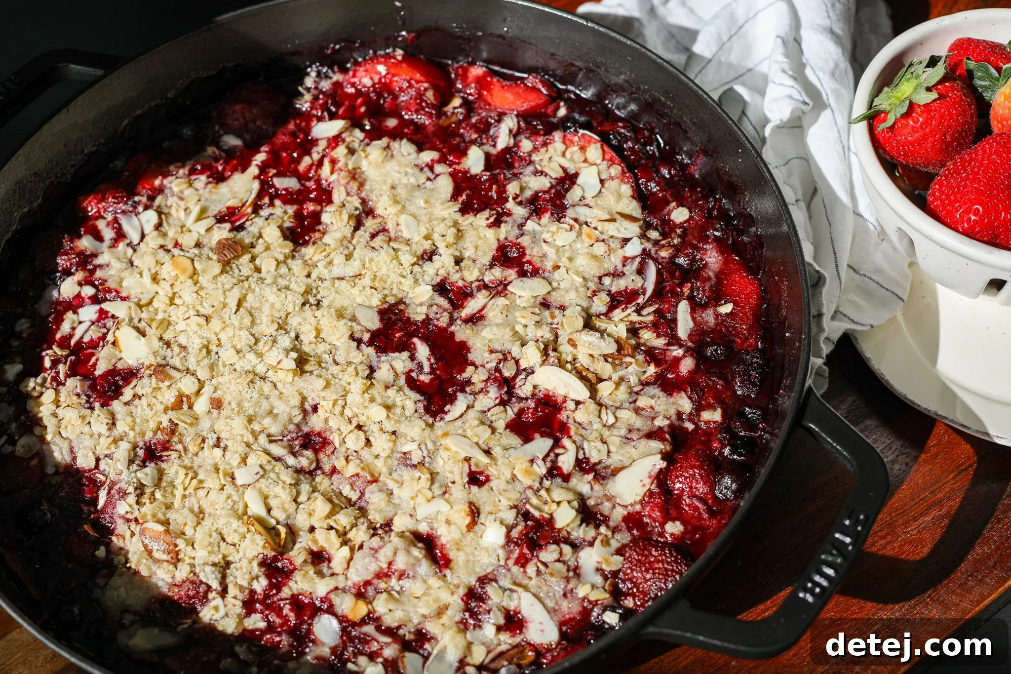 Side angle shot of a freshly baked Peachberry Crisp, showing the golden crumb topping and bubbling fruit filling.