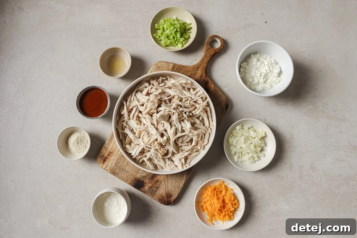 A vibrant display of fresh ingredients, including shredded chicken, cottage cheese, buffalo sauce, and crisp vegetables, laid out for a spicy buffalo chicken salad.