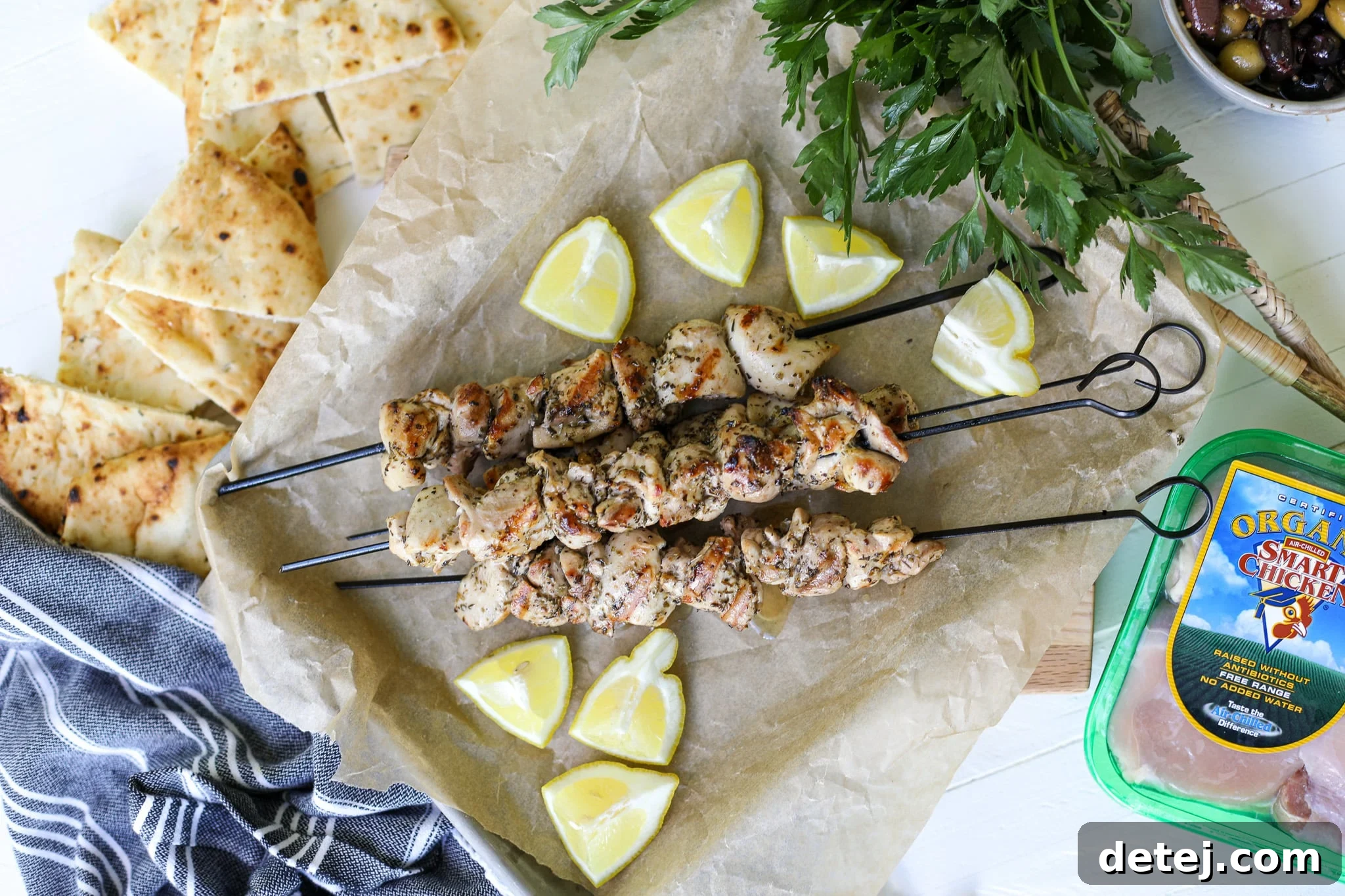 Overhead shot of grilled Greek chicken souvlaki on a platter with fresh herbs.
