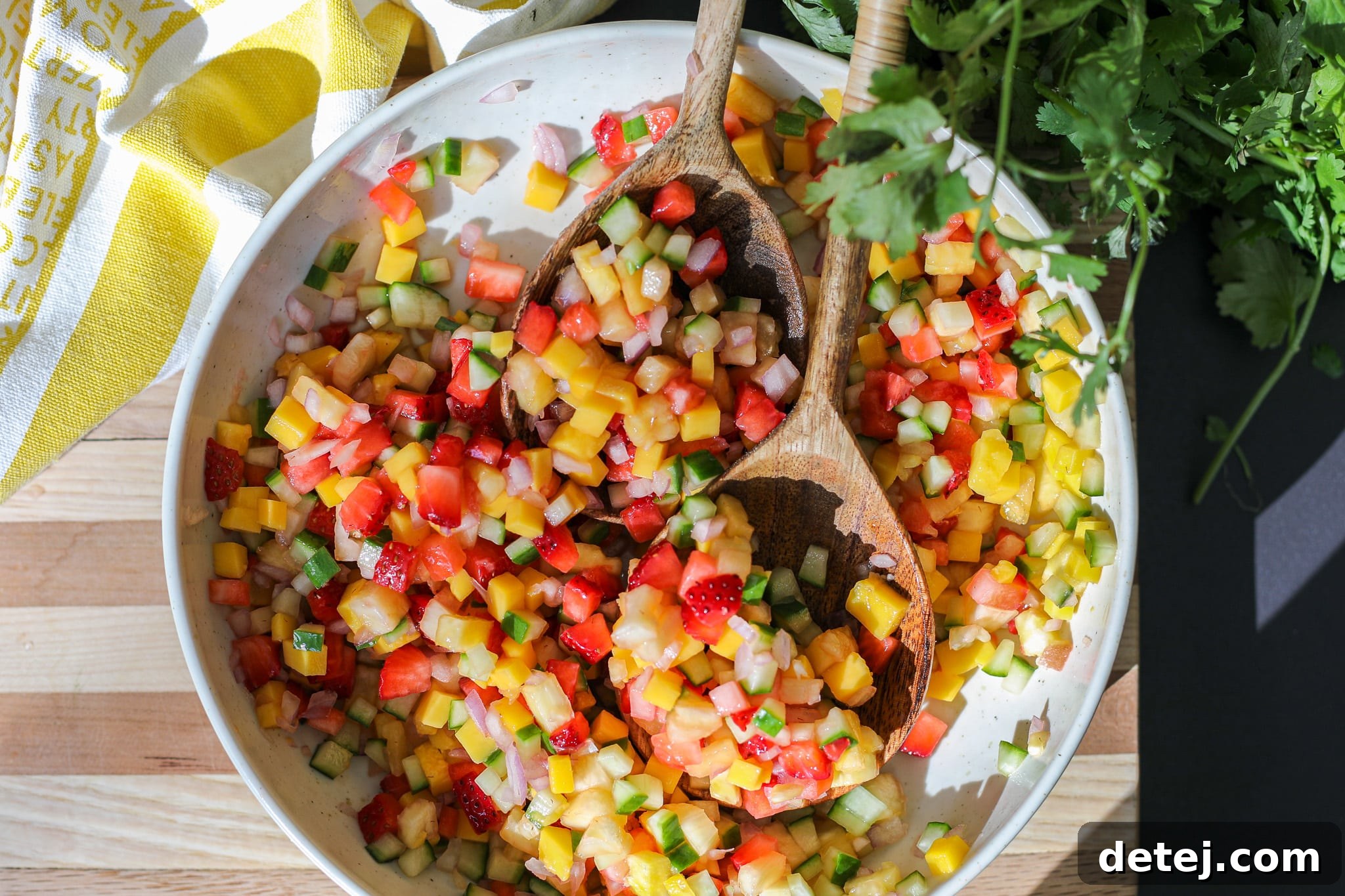 Overhead shot of freshly diced ingredients for fruit salsa, meticulously arranged in separate piles, including pineapple, mango, strawberries, cucumber, and shallots.