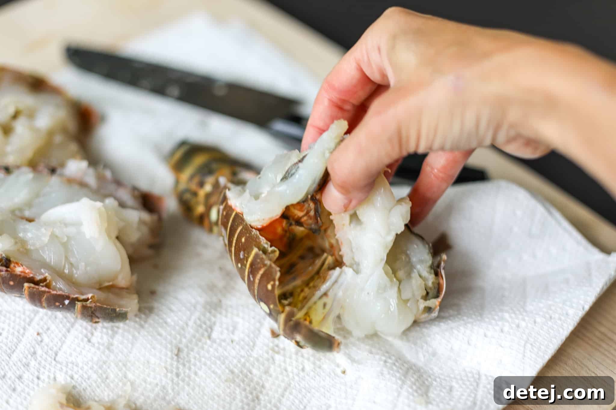 Gently releasing the lobster meat from its shell to butterfly it, ensuring it doesn't stick.