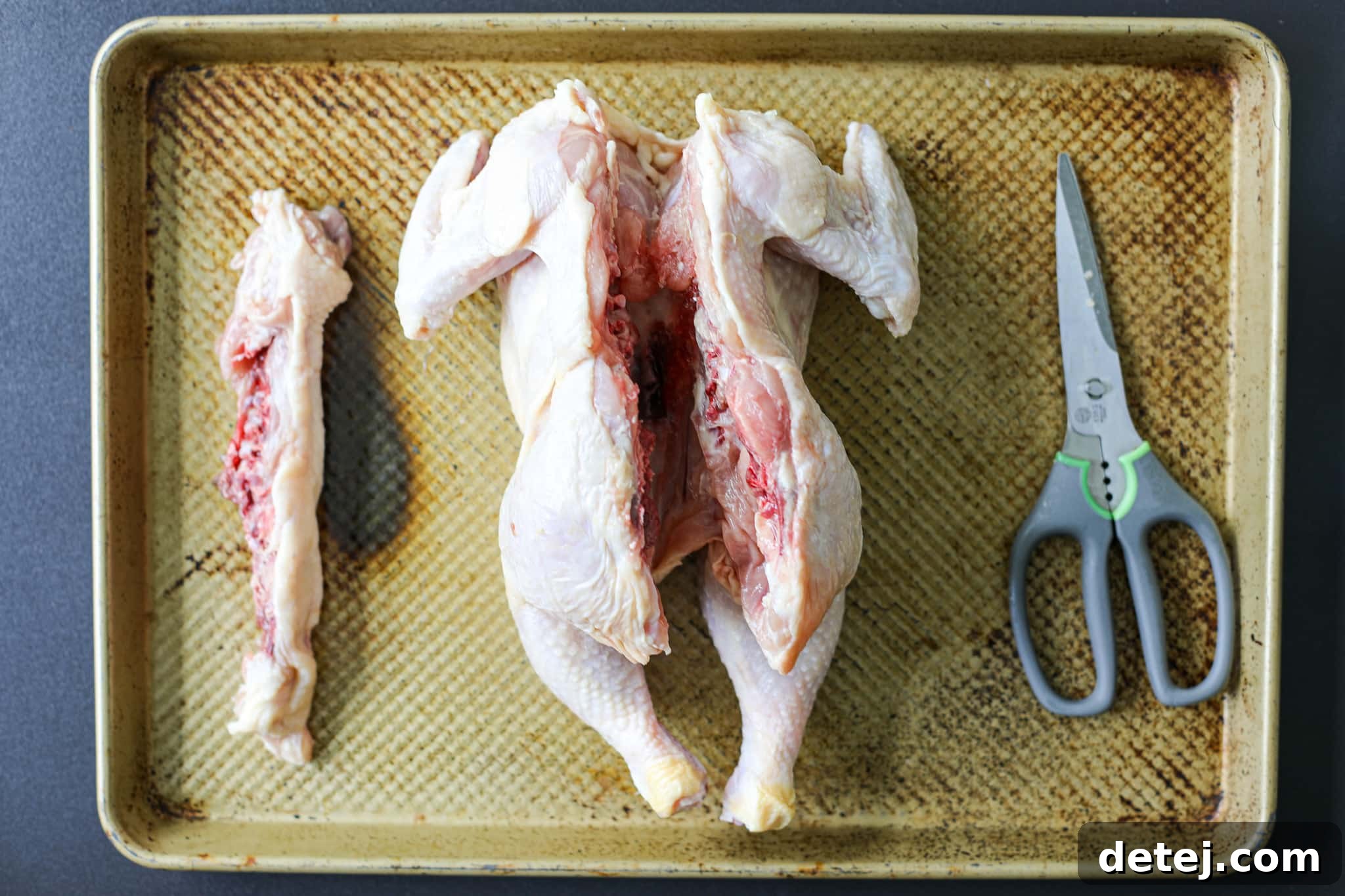 Spatchcocked whole chicken with backbone removed, ready for seasoning.