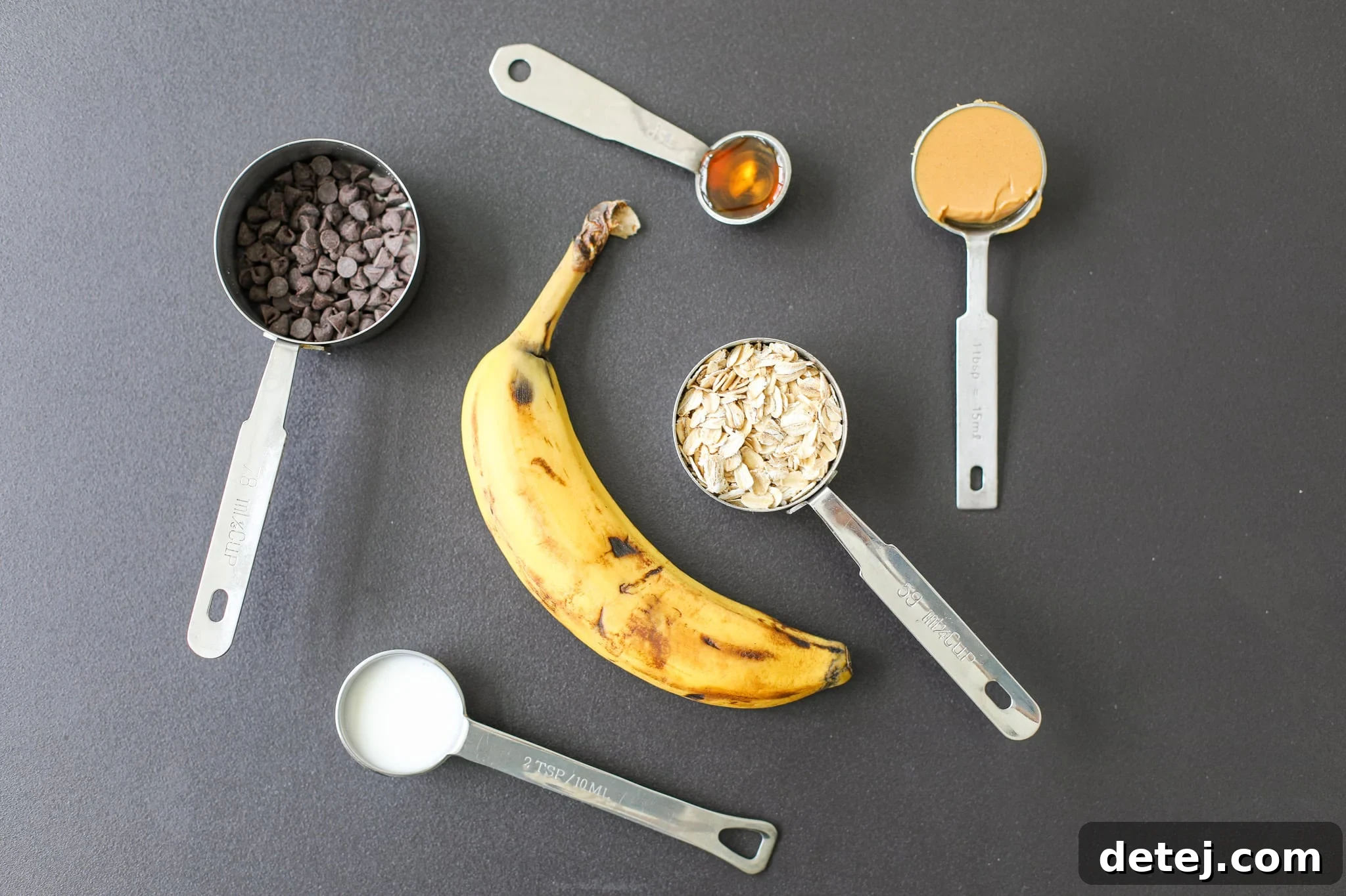 Flourless Peanut Butter Oatmeal Cookie for One 3 A beautifully arranged flat lay of all the essential ingredients for the peanut butter oatmeal cookie, including oats, banana, peanut butter, milk, and chocolate chips.