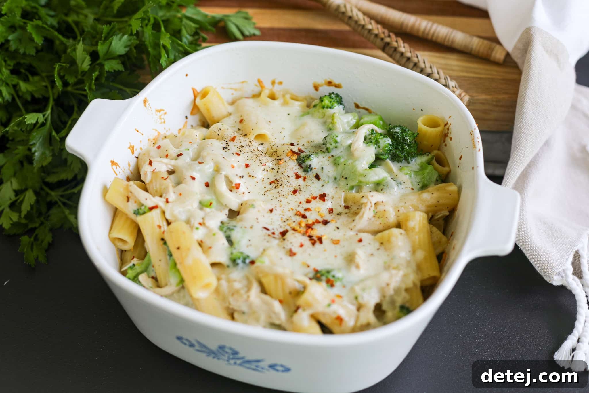 A tempting side shot of the cheesy, creamy chicken broccoli pasta bake in a casserole dish.