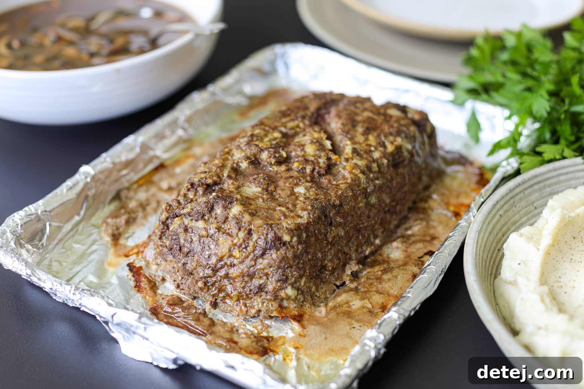 Freshly baked meatloaf generously topped with homemade mushroom gravy, ready to be served from a sheet pan.
