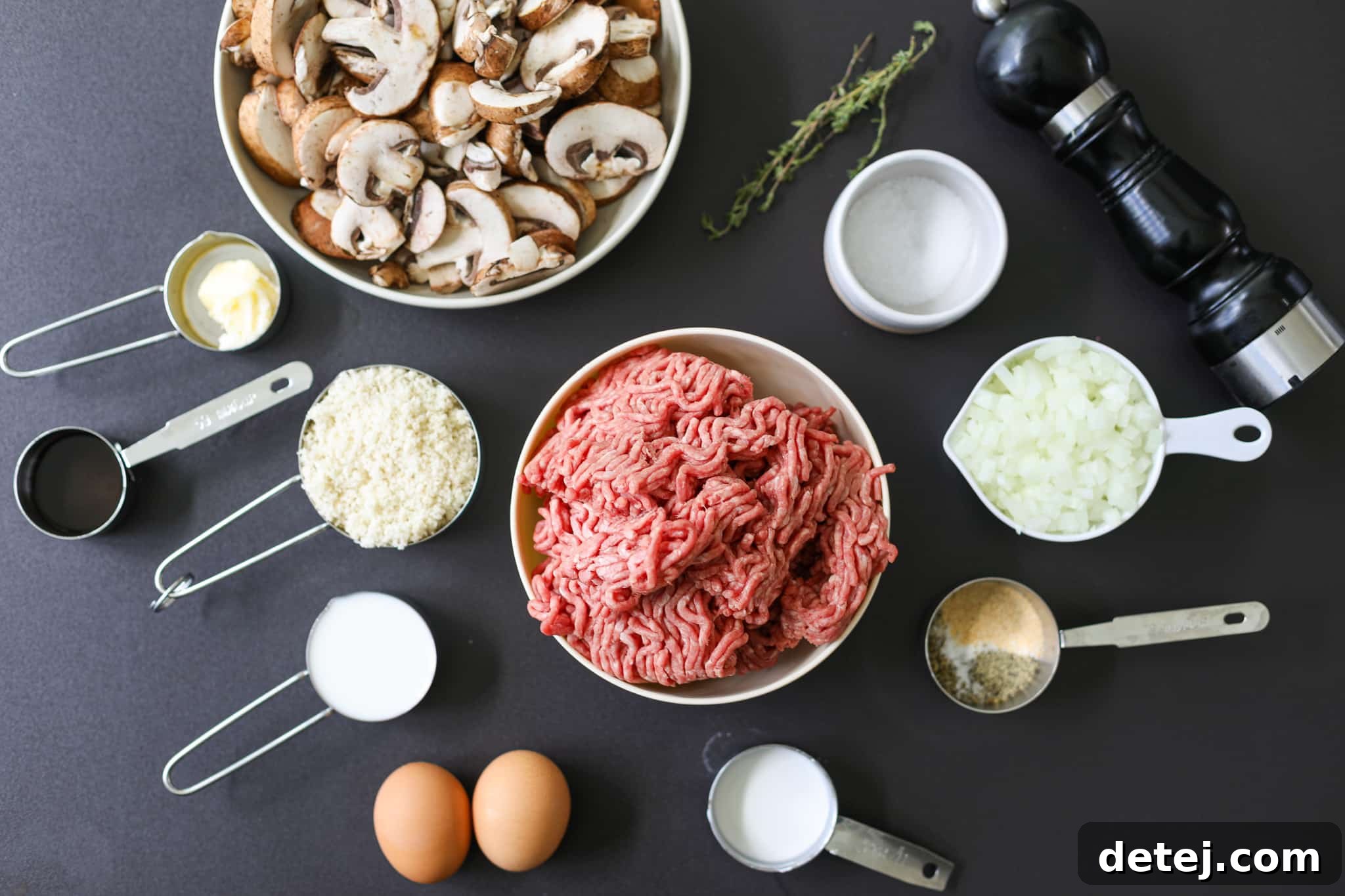 Assortment of fresh ingredients for Marry Me Meatloaf and Mushroom Gravy, including ground beef, eggs, milk, onions, mushrooms, and various seasonings.