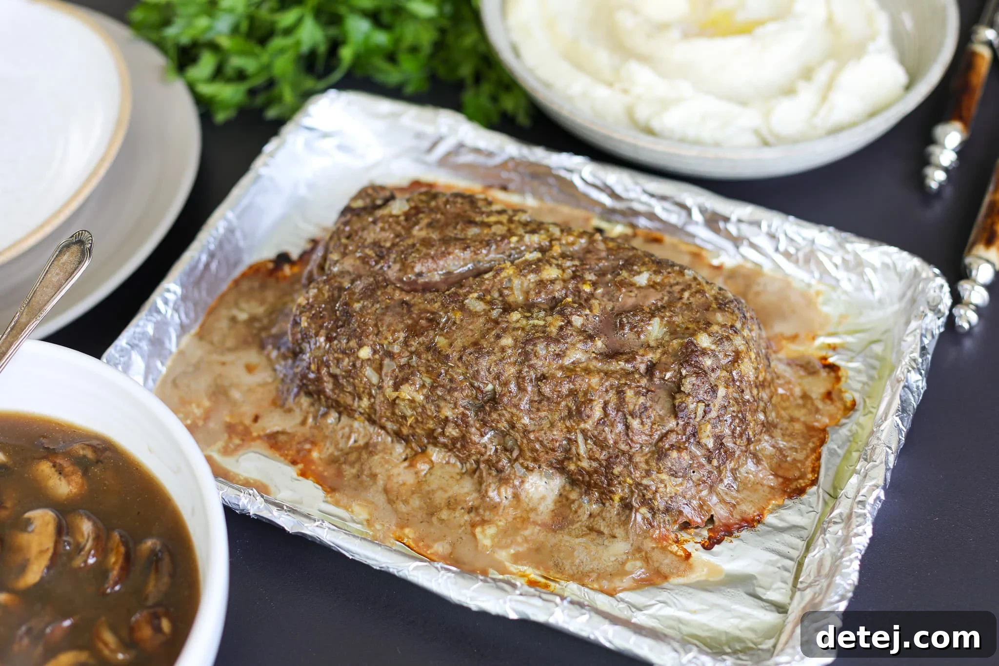 A full comforting dinner plate with sliced meatloaf, mashed potatoes, and rich mushroom gravy.