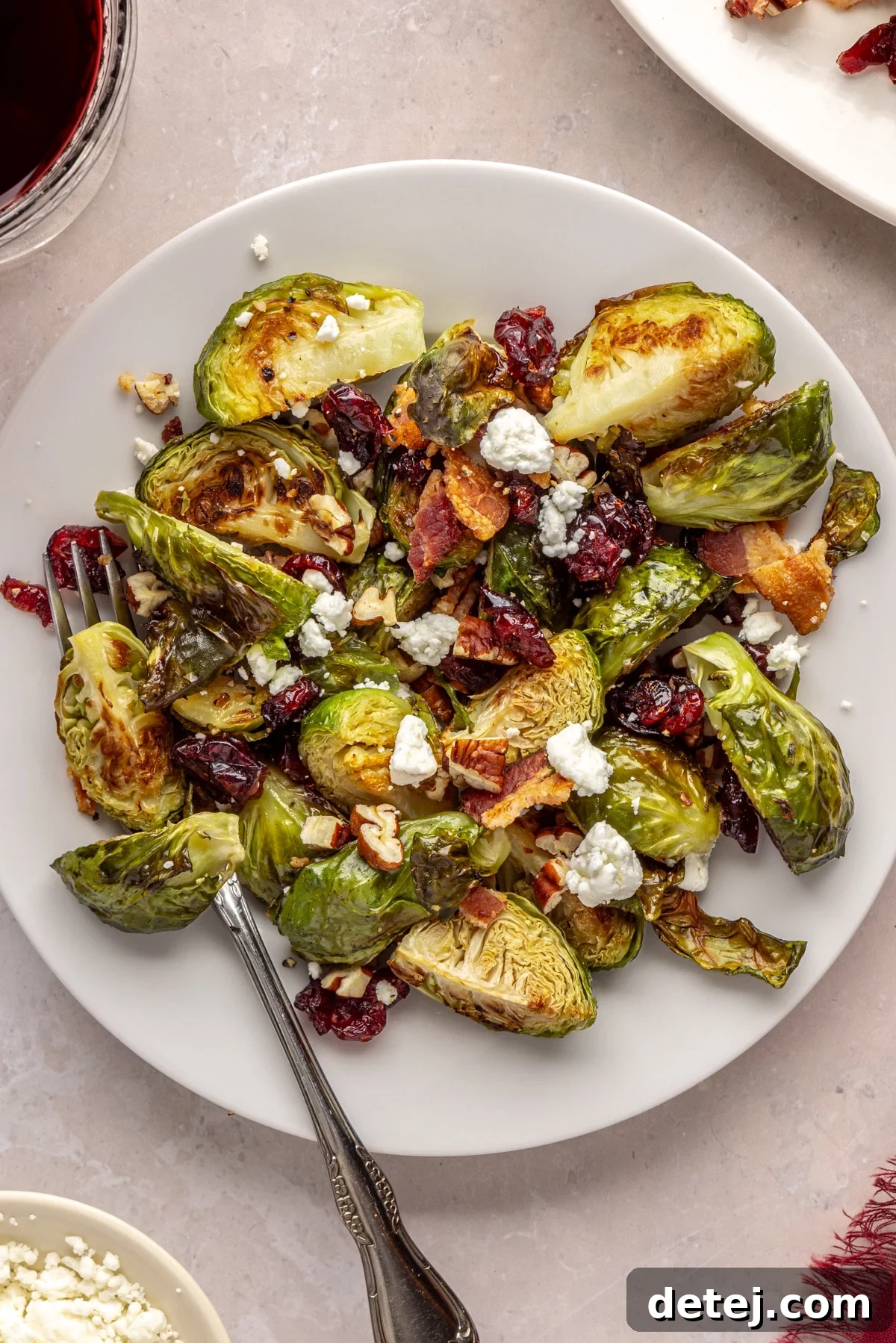 Close-up of fresh Brussels sprouts, avocado oil, kosher salt, black pepper, bacon, pecans, dried cranberries, and goat cheese on a wooden board.