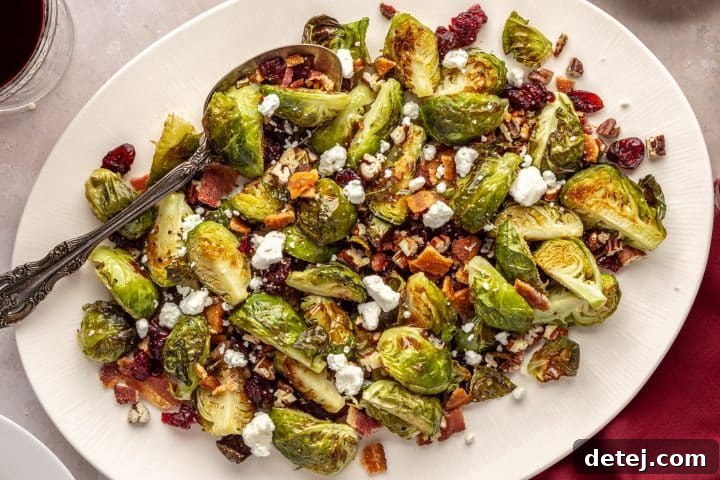 Roasted Brussels Sprouts with Bacon, Pecans, Cranberries, and Goat Cheese topped with crumbled goat cheese on a serving platter.