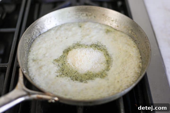 creamy pesto sauce in a pan with parmesan cheese sprinkled on top.