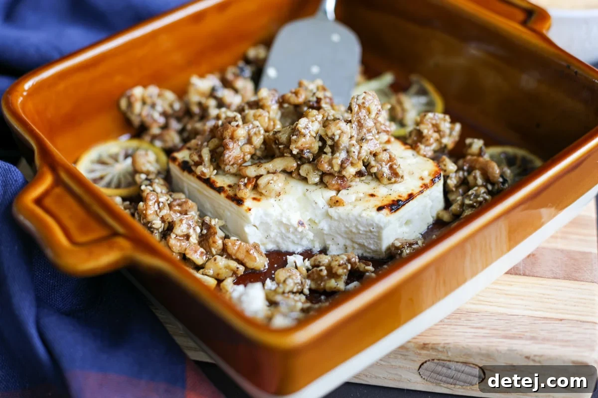 A serving of baked feta with honey and sticky walnuts, showing the creamy interior and crunchy topping.