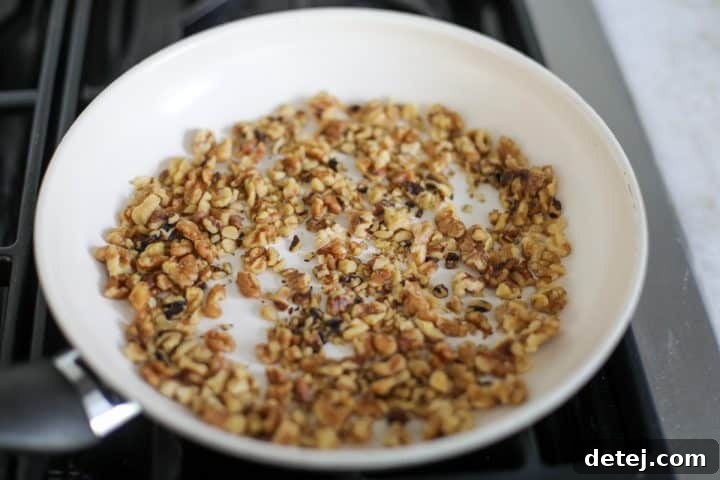 Raw walnut pieces are placed in a nonstick skillet, ready for toasting.