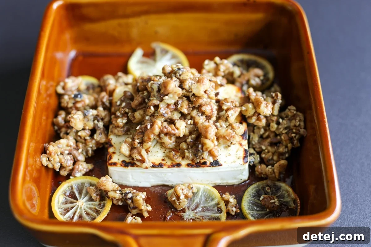 A vibrant platter of baked feta with honey and sticky walnuts, garnished with fresh herbs and lemon slices, ready to be enjoyed.