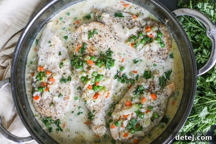 Finished Creamy Chicken and Vegetables dish in a pan, garnished with fresh parsley.