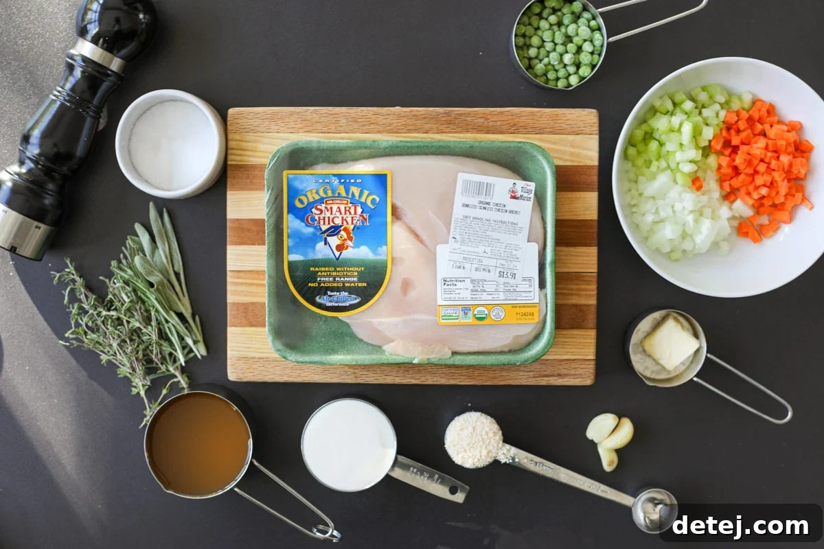 A vibrant selection of fresh ingredients, including chicken, various vegetables, herbs, and seasonings, laid out for the creamy chicken dish.