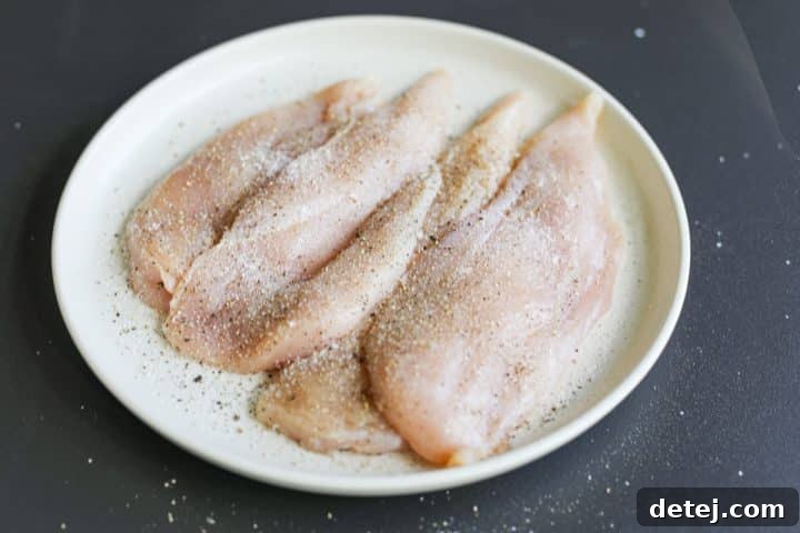 Butterflied chicken cutlets seasoned with salt and pepper on a white plate.
