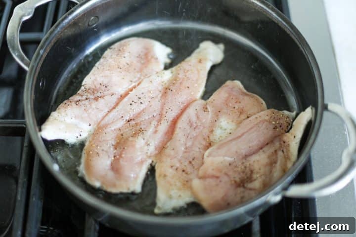 Seasoned chicken cutlets sizzling in a hot sauté pan with avocado oil.