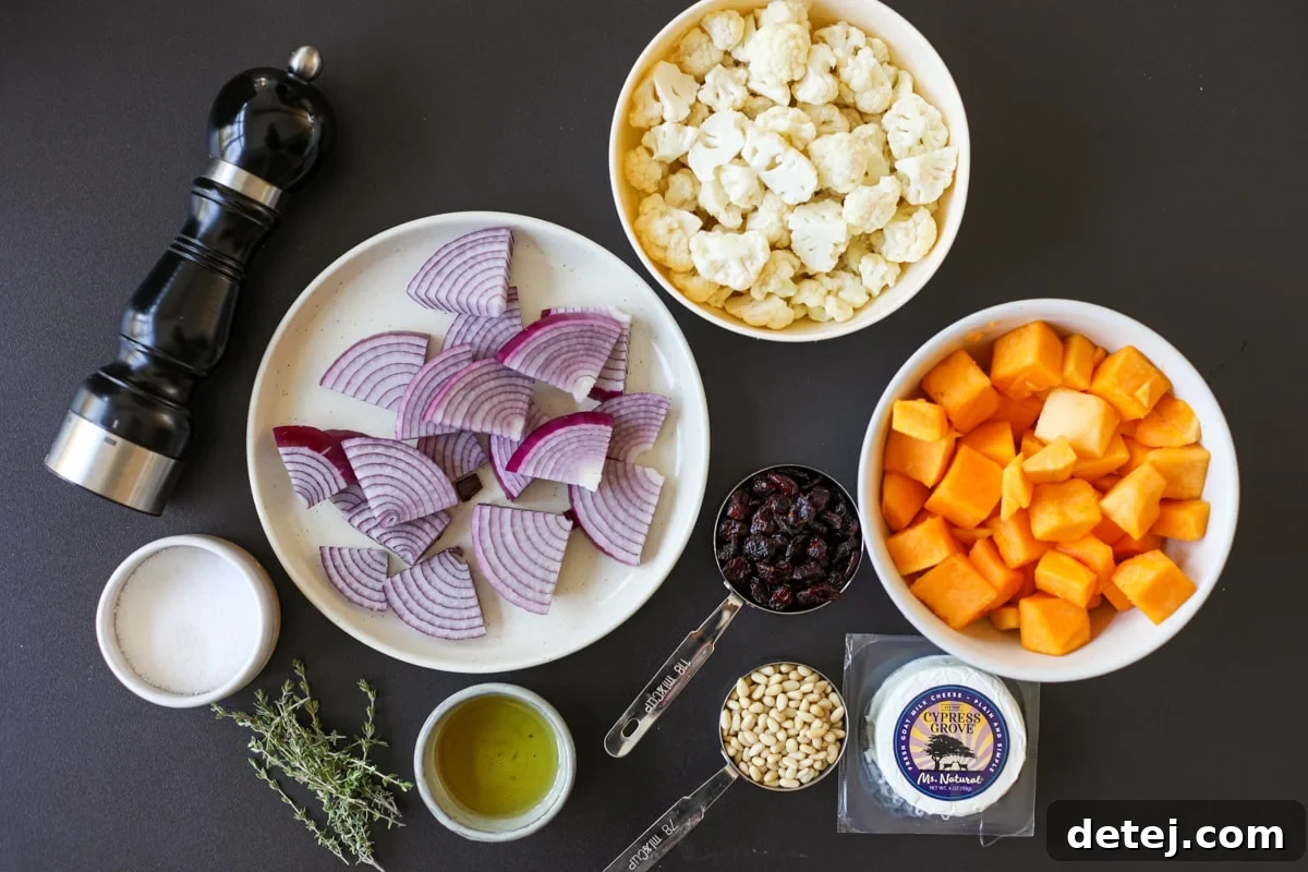 A tray filled with fresh ingredients including cubed butternut squash, cauliflower florets, and sliced red onion, ready for roasting.
