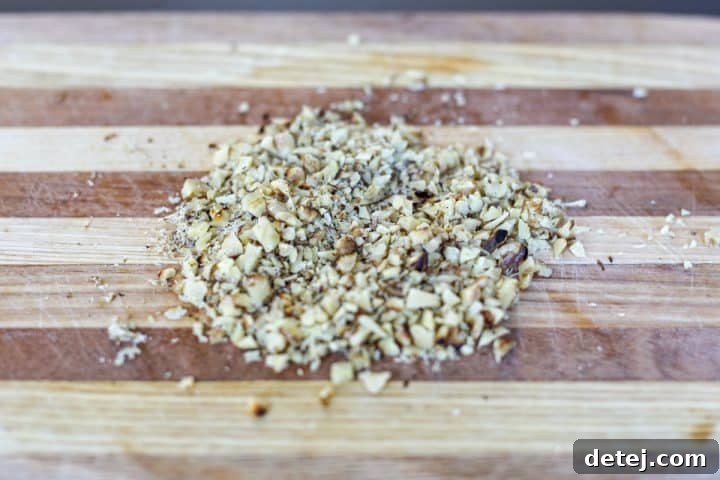 Toasted walnuts, finely chopped on a cutting board.