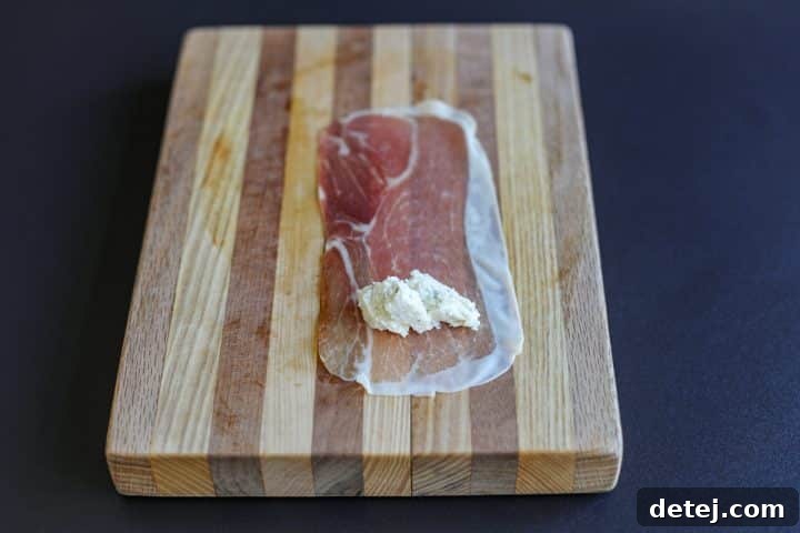 Boursin cheese being added to one end of a prosciutto slice.