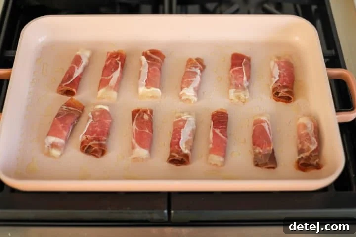 Prosciutto roll-ups pan-searing in a griddle pan to achieve crispiness.