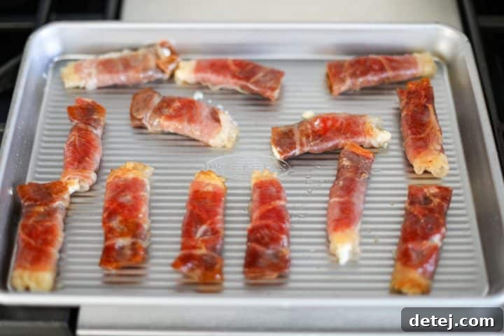 Crispy prosciutto wraps arranged on a serving tray after searing.