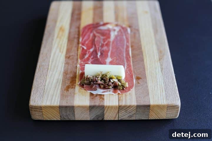 Prosciutto slice with mozzarella cheese and a sprinkle of chopped mixed olives.