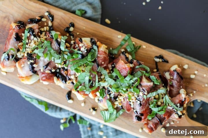 Finished Crispy Prosciutto and Mozzarella Roll-Ups arranged on a serving platter, drizzled with balsamic glaze, sprinkled with pine nuts and fresh basil.