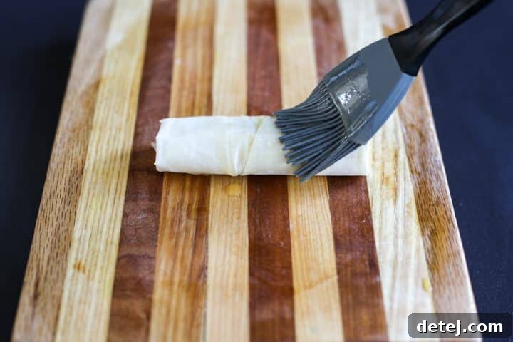 Assembled brie and date roll-ups generously brushed with melted butter for a rich, golden finish