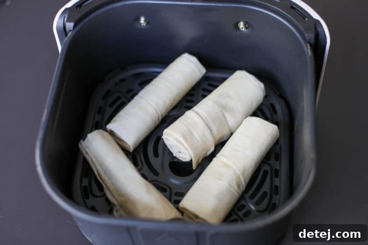 Golden-brown brie and date roll-ups perfectly air-fried in the basket, awaiting final garnish