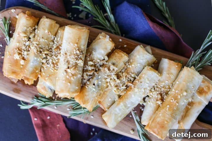 Crispy Phyllo Wrapped Brie Roll-Ups (Air Fryer) beautifully garnished with honey, walnuts, and sesame seeds on a serving platter