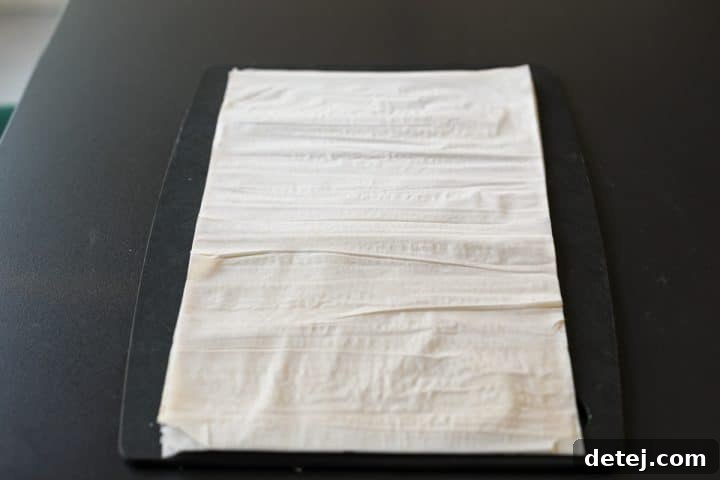 Delicate phyllo dough sheets gently unrolled and laid flat on a clean surface