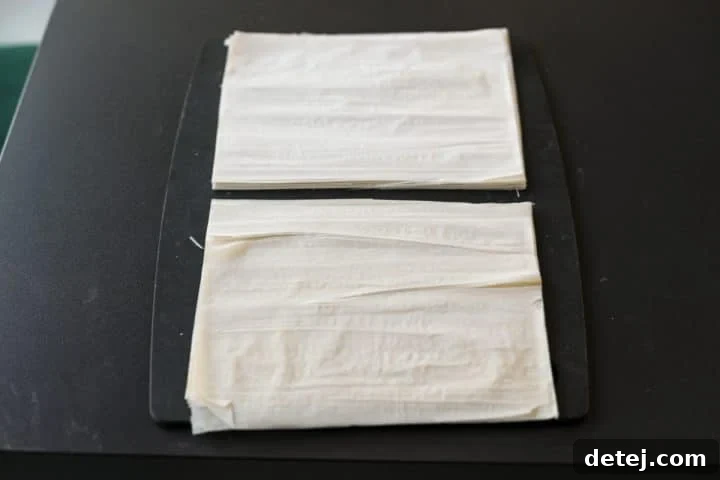 Phyllo dough stack neatly cut in half widthwise for smaller, manageable pieces